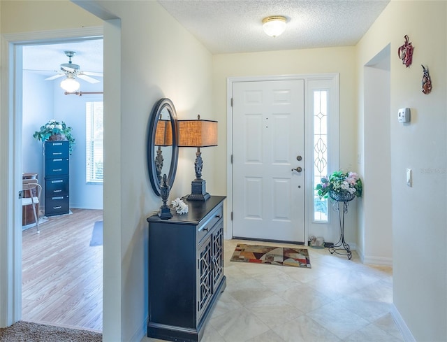 foyer featuring a textured ceiling, baseboards, and a ceiling fan