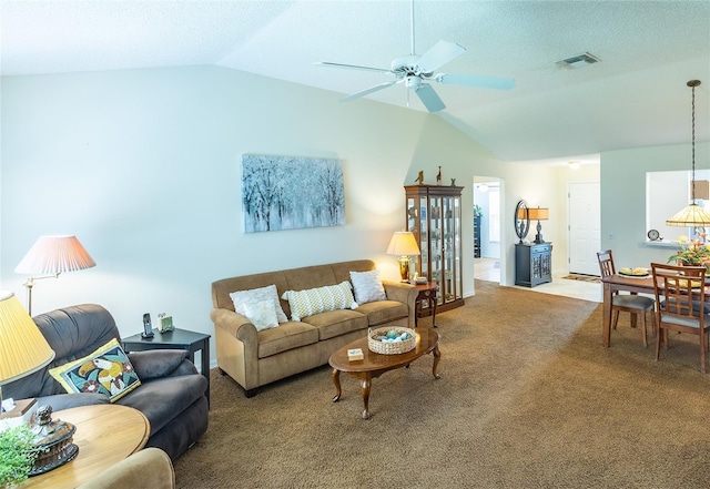 carpeted living room with visible vents, vaulted ceiling, and ceiling fan