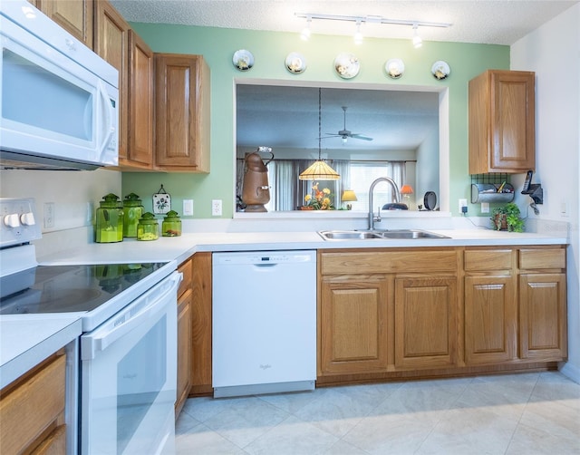 kitchen featuring white appliances, light countertops, a sink, and brown cabinets