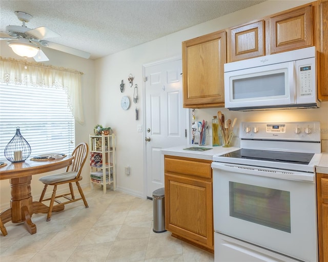 kitchen featuring baseboards, white appliances, a textured ceiling, light countertops, and ceiling fan