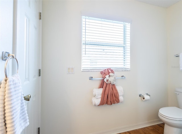 bathroom featuring toilet, wood finished floors, and baseboards