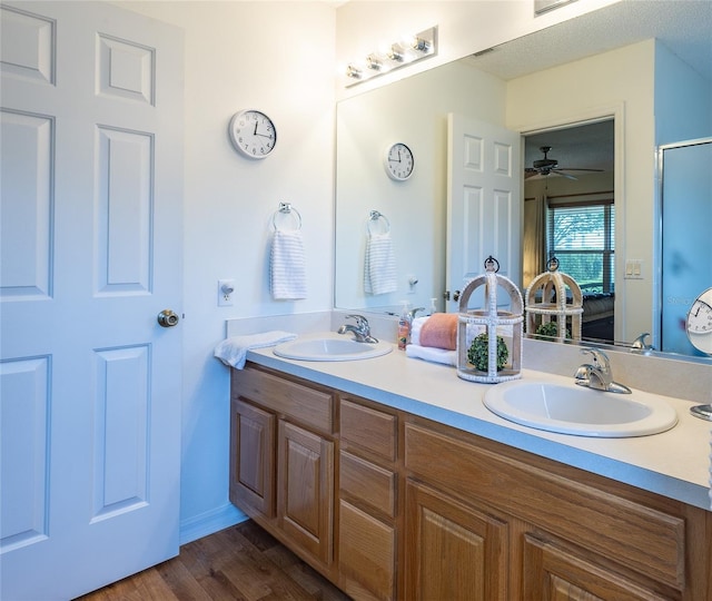 ensuite bathroom with a sink, ensuite bathroom, double vanity, and wood finished floors