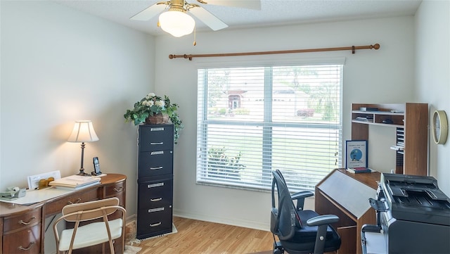 home office with light wood-type flooring, a healthy amount of sunlight, ceiling fan, and baseboards