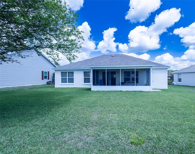rear view of property with a sunroom, roof with shingles, and a lawn