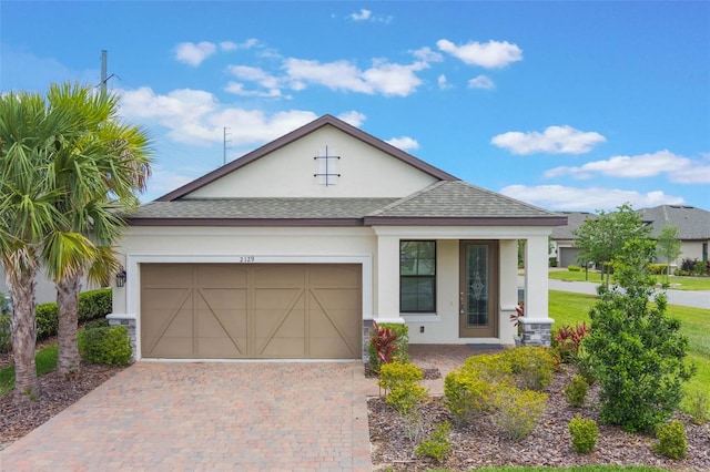 2129 Palm Tree Dr, Poinciana, FL 34759 - view of front facade featuring a porch, an attached garage, a shingled roof, stucco siding, and decorative driveway