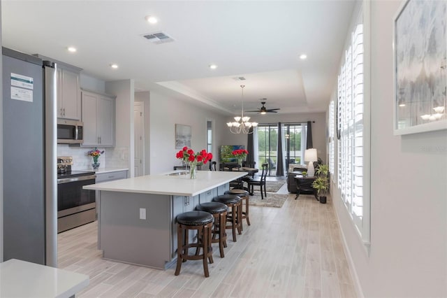 2129 Palm Tree Dr, Poinciana, FL 34759 - kitchen with stainless steel appliances, a raised ceiling, gray cabinetry, visible vents, and recessed lighting
