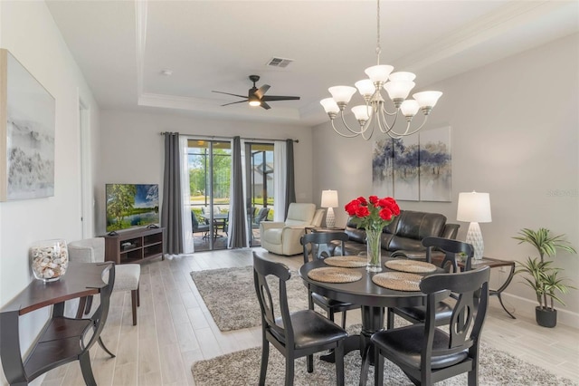 2129 Palm Tree Dr, Poinciana, FL 34759 - dining area with baseboards, visible vents, light wood-style floors, ceiling fan with notable chandelier, and a raised ceiling