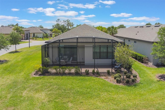 2129 Palm Tree Dr, Poinciana, FL 34759 - back of house with a patio area, glass enclosure, a yard, roof with shingles, and a residential view