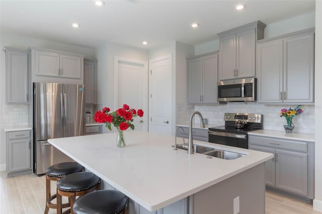2129 Palm Tree Dr, Poinciana, FL 34759 - kitchen featuring a sink, a center island with sink, stainless steel appliances, and gray cabinetry