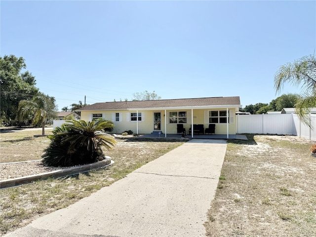 ranch-style home featuring a porch, driveway, and fence