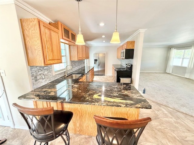 kitchen featuring appliances with stainless steel finishes, dark stone countertops, crown molding, decorative backsplash, and a sink