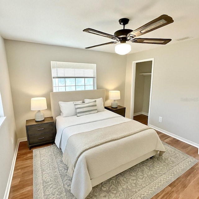 bedroom with visible vents, baseboards, a ceiling fan, and wood finished floors