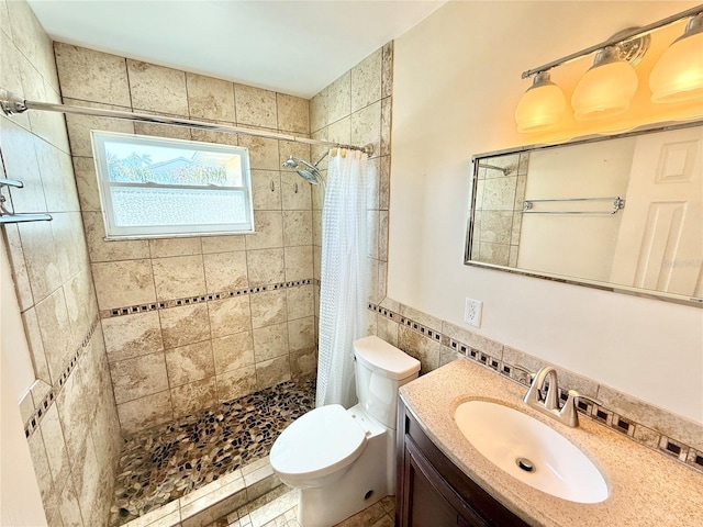 bathroom featuring tile walls, toilet, a stall shower, and vanity