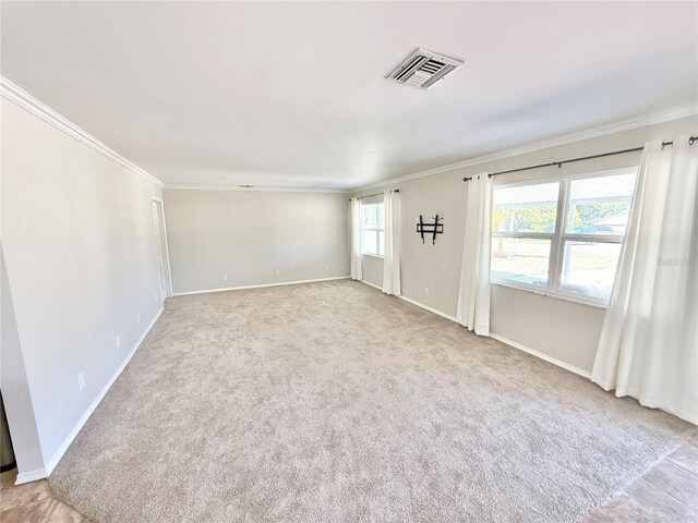 carpeted empty room featuring baseboards, ornamental molding, and visible vents