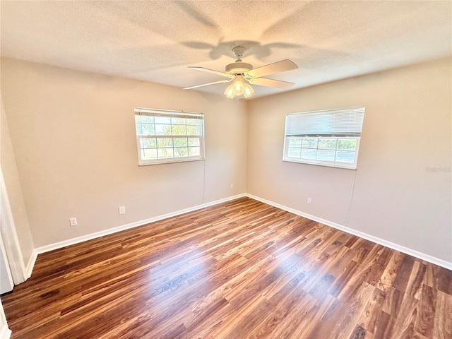 empty room with a textured ceiling, wood finished floors, ceiling fan, and baseboards