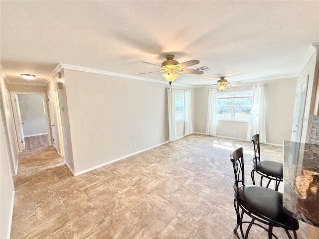 interior space featuring stone finish floor, baseboards, a ceiling fan, and ornamental molding
