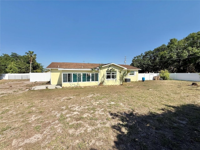 rear view of house with a yard, a fenced backyard, and cooling unit