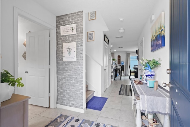 foyer with light tile patterned floors, stairs, and baseboards