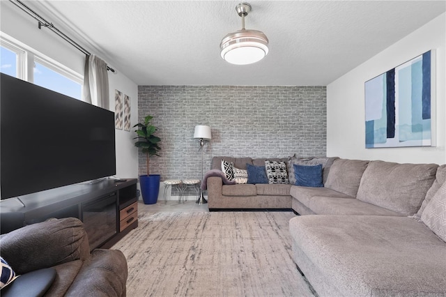 living area featuring a textured ceiling and brick wall