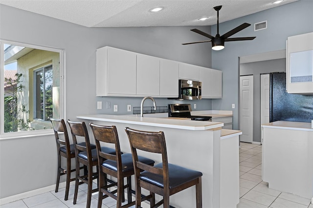 14 Clear Ct, Palm Coast, FL 32137 - kitchen with a peninsula, a textured ceiling, visible vents, light countertops, and stainless steel appliances