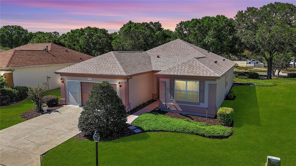 single story home with concrete driveway, a shingled roof, a yard, a garage, and stucco siding