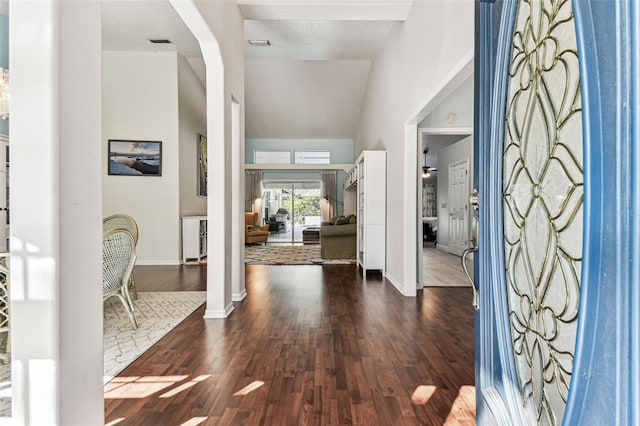 foyer with baseboards, vaulted ceiling, wood finished floors, and visible vents