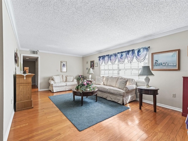 living area with a textured ceiling, visible vents, light wood-type flooring, and ornamental molding