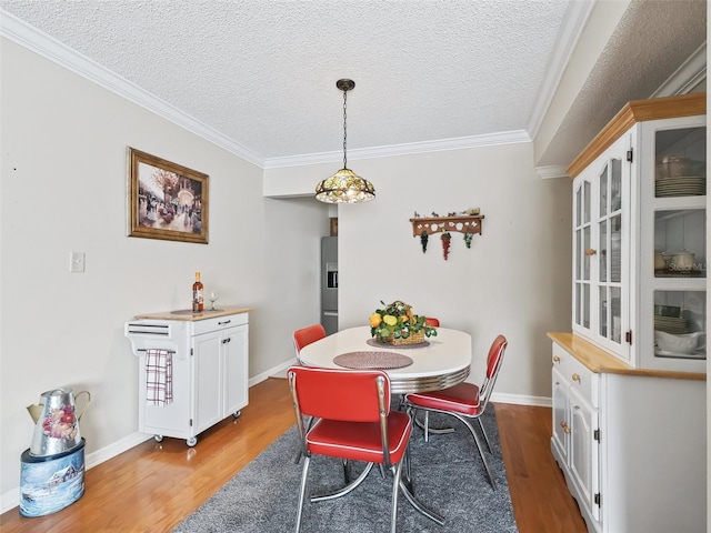 dining room featuring ornamental molding, a textured ceiling, and wood finished floors