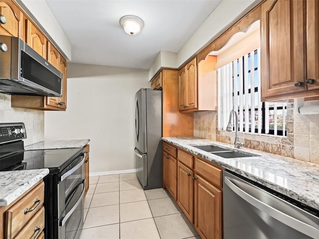 kitchen with tasteful backsplash, light stone counters, appliances with stainless steel finishes, and a sink