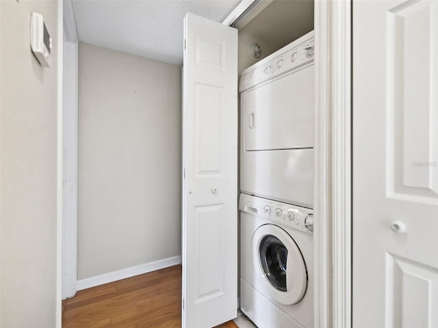 washroom with light wood-style floors, stacked washer / dryer, laundry area, and baseboards
