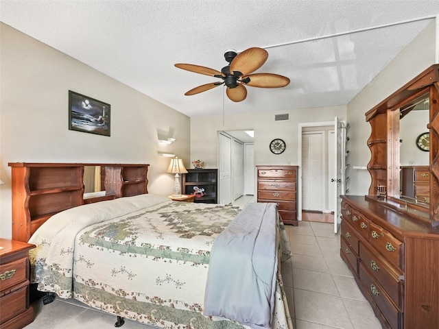 bedroom with light tile patterned floors, a ceiling fan, visible vents, and a textured ceiling