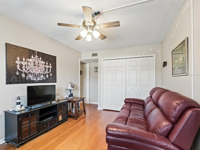 living room featuring a ceiling fan, visible vents, a textured ceiling, and light wood-style floors