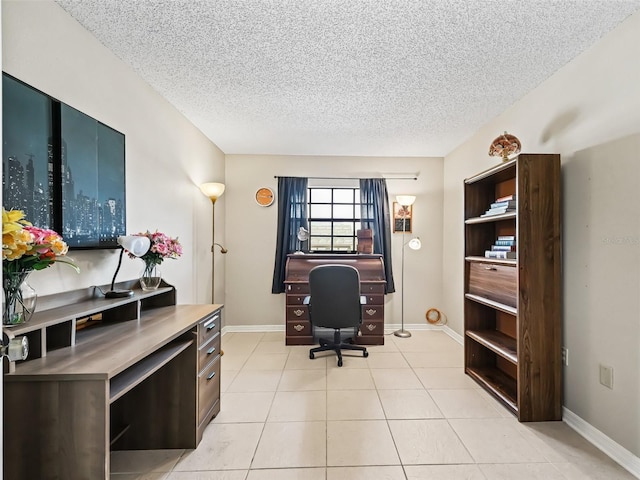 office area with a textured ceiling, light tile patterned floors, and baseboards