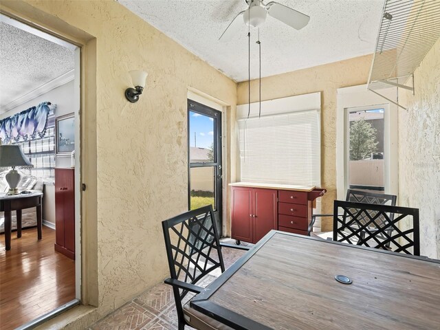 dining space with a textured ceiling, a ceiling fan, and a textured wall