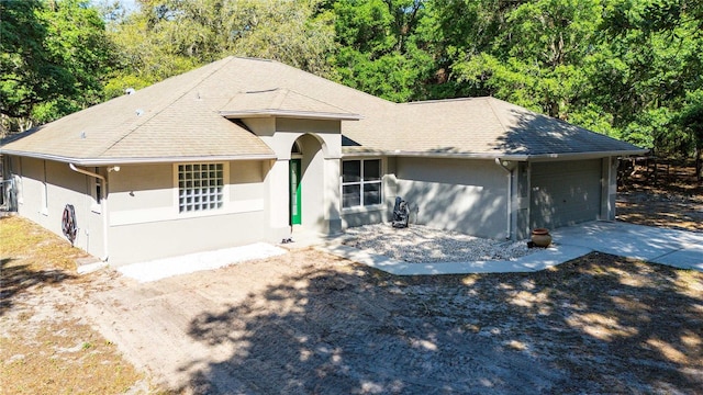 single story home with a garage, stucco siding, concrete driveway, and roof with shingles