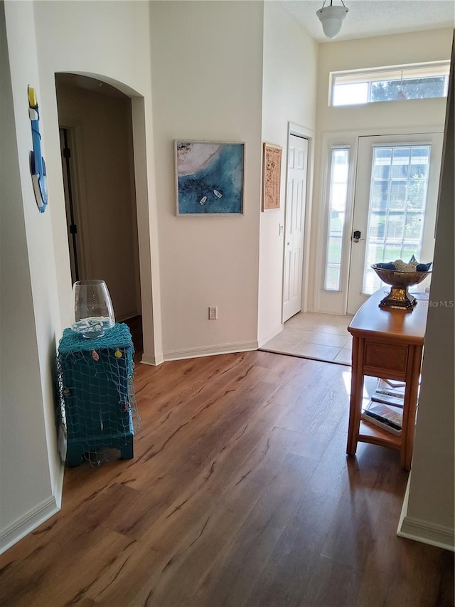 entrance foyer with wood finished floors, baseboards, and arched walkways