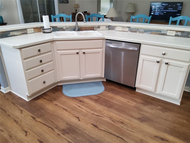 kitchen featuring wood finished floors, light countertops, dishwasher, a sink, and white cabinetry