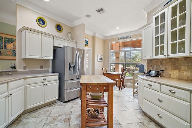 kitchen featuring light countertops, stainless steel fridge, tasteful backsplash, and ornamental molding