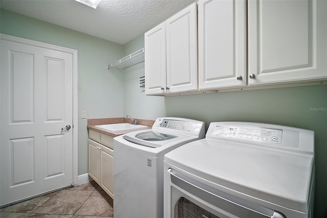 laundry area featuring a sink, a textured ceiling, light tile patterned flooring, cabinet space, and independent washer and dryer