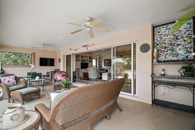 living room featuring a ceiling fan, baseboards, and a textured ceiling