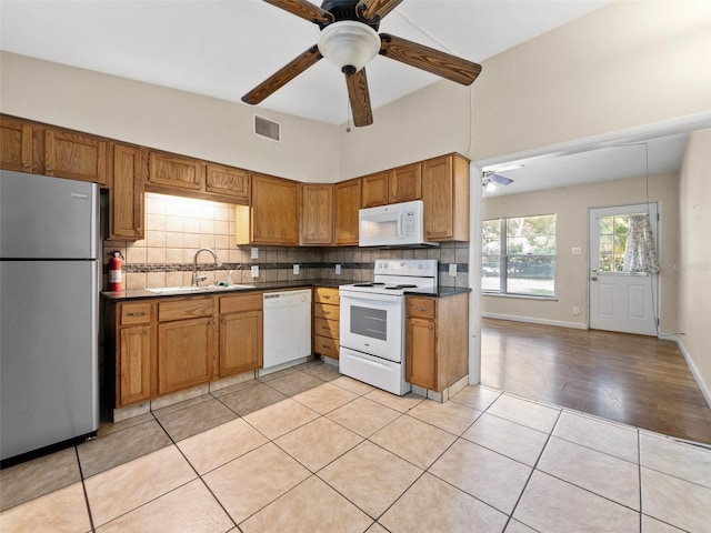 25519 Colmar Ave, Sorrento, FL 32776 - kitchen with white appliances, a sink, ceiling fan, backsplash, and dark countertops