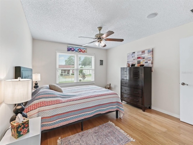 9621 SE 168th Maplesong Ln, The Villages, FL 32162 - bedroom with a ceiling fan, a textured ceiling, baseboards, and light wood-type flooring