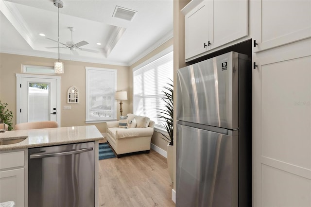 12129 Grand Oak Ln, Oxford, FL 34484 - kitchen with ceiling fan, stainless steel appliances, light wood-style flooring, visible vents, and a raised ceiling