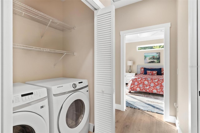 12129 Grand Oak Ln, Oxford, FL 34484 - clothes washing area with washer and dryer, baseboards, laundry area, and light wood-style flooring