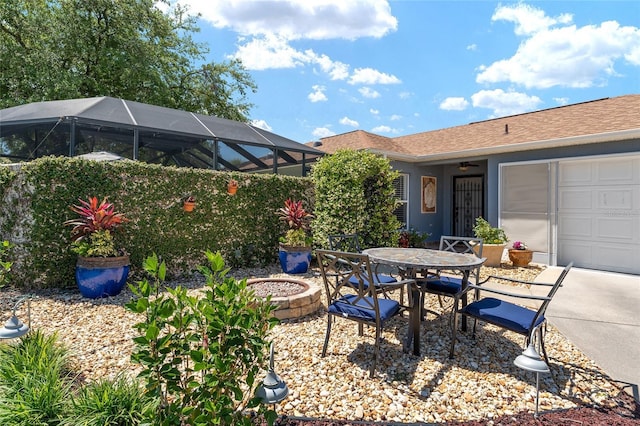 view of patio / terrace featuring ceiling fan, outdoor dining area, a lanai, a fire pit, and a garage