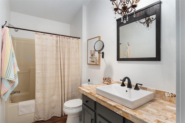 full bathroom with a chandelier, shower / tub combo with curtain, toilet, and vanity