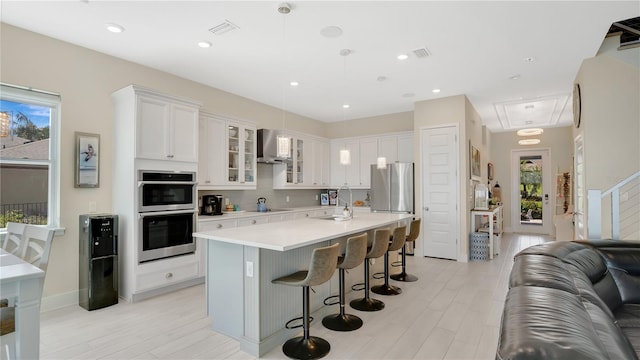 26516 Savage Cir, Howey In The Hills, FL 34737 - kitchen with wall chimney exhaust hood, light countertops, a kitchen breakfast bar, open floor plan, and stainless steel appliances