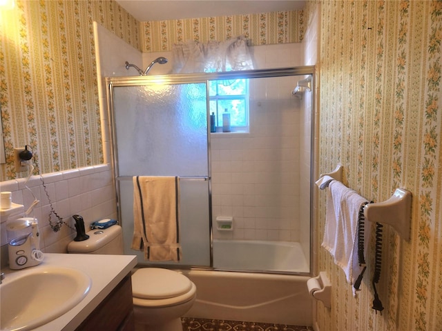 full bathroom featuring vanity, toilet, enclosed tub / shower combo, tile walls, and wallpapered walls