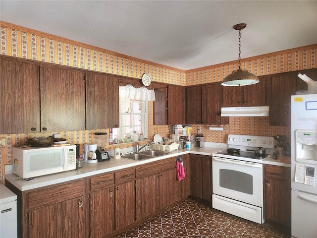 kitchen with wallpapered walls, white appliances, light countertops, under cabinet range hood, and a sink