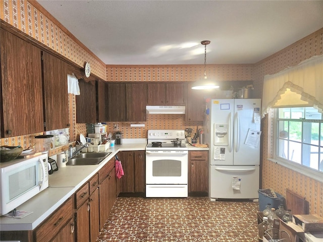 kitchen featuring a sink, light countertops, white appliances, under cabinet range hood, and wallpapered walls